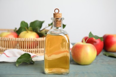 Photo of Natural apple vinegar and fresh fruits on blue wooden table