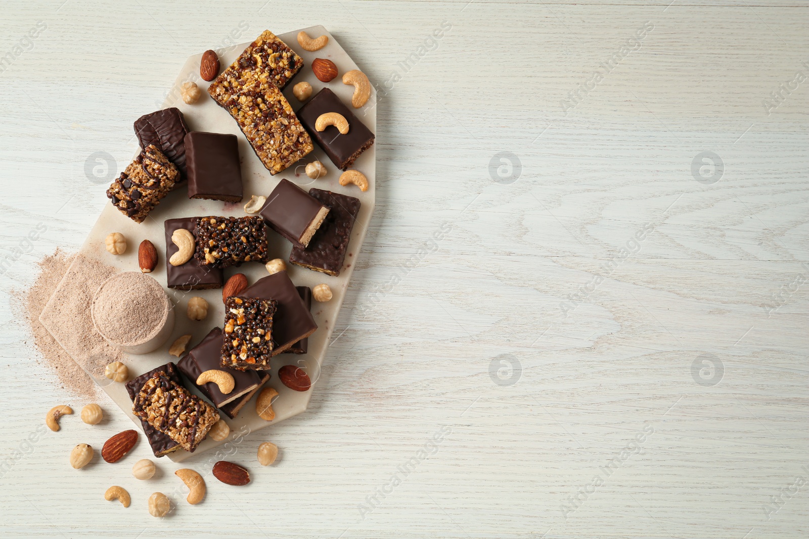 Photo of Different tasty energy bars, protein powder and nuts on white wooden table, flat lay. Space for text