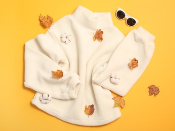Photo of Flat lay composition with sweater and dry leaves on yellow background. Autumn season