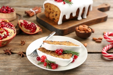 Photo of Traditional classic Christmas cake decorated with cranberries, pomegranate and rosemary on wooden table