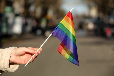Photo of Woman holding bright LGBT flag on city street, closeup