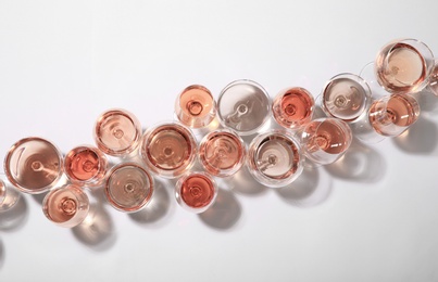 Different glasses with rose wine on white background, top view