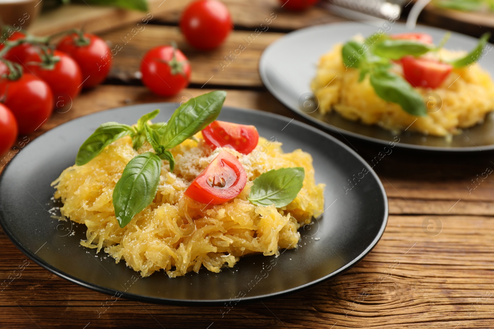 Photo of Tasty spaghetti squash with tomatoes and basil served on wooden table