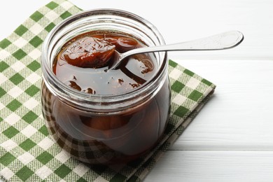 Photo of Jar of tasty sweet fig jam on white wooden table