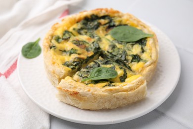 Photo of Delicious pie with spinach on white tiled table, closeup