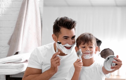 Photo of Father and son having fun while shaving in bathroom