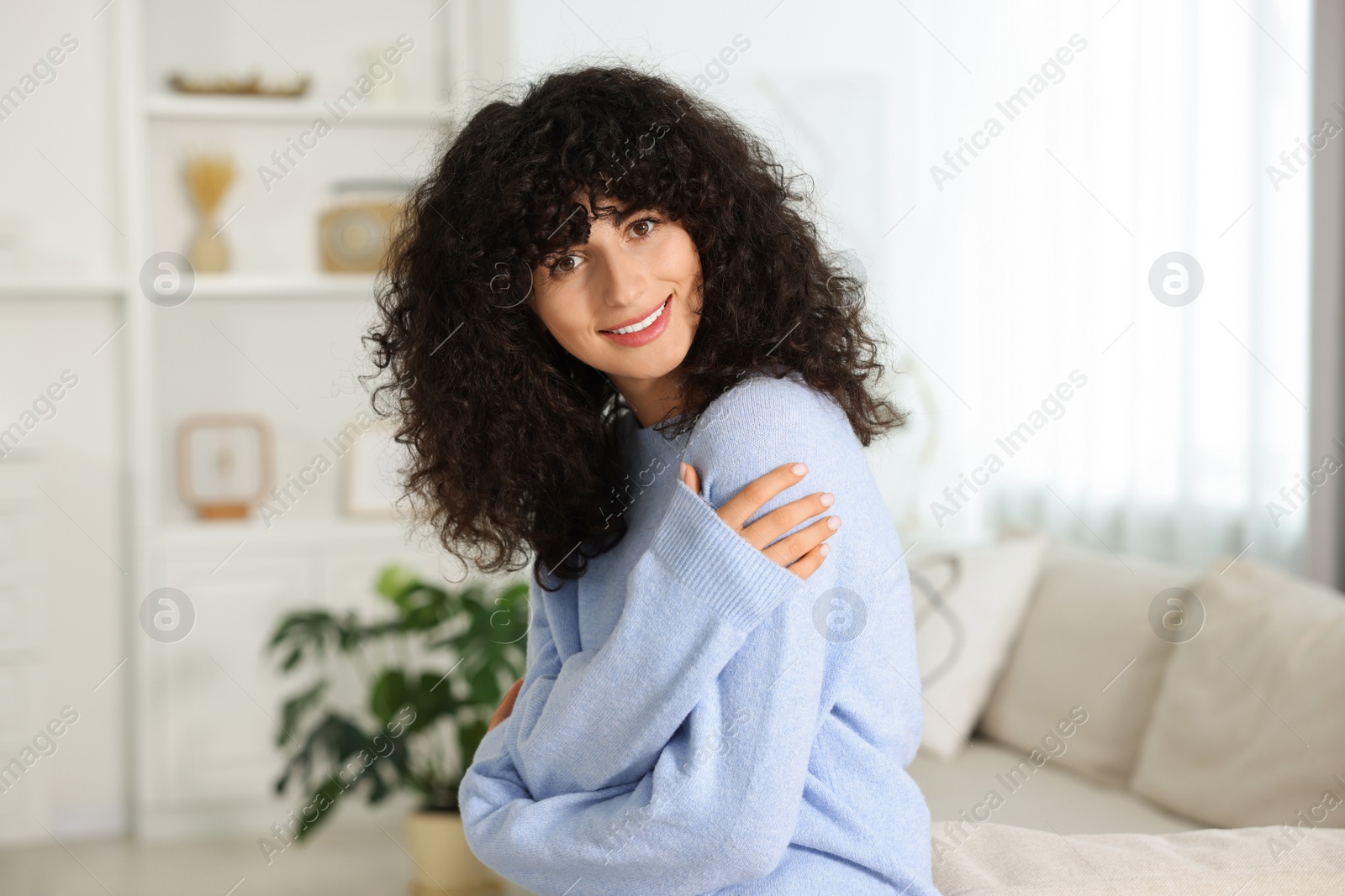 Photo of Happy young woman in stylish light blue sweater indoors