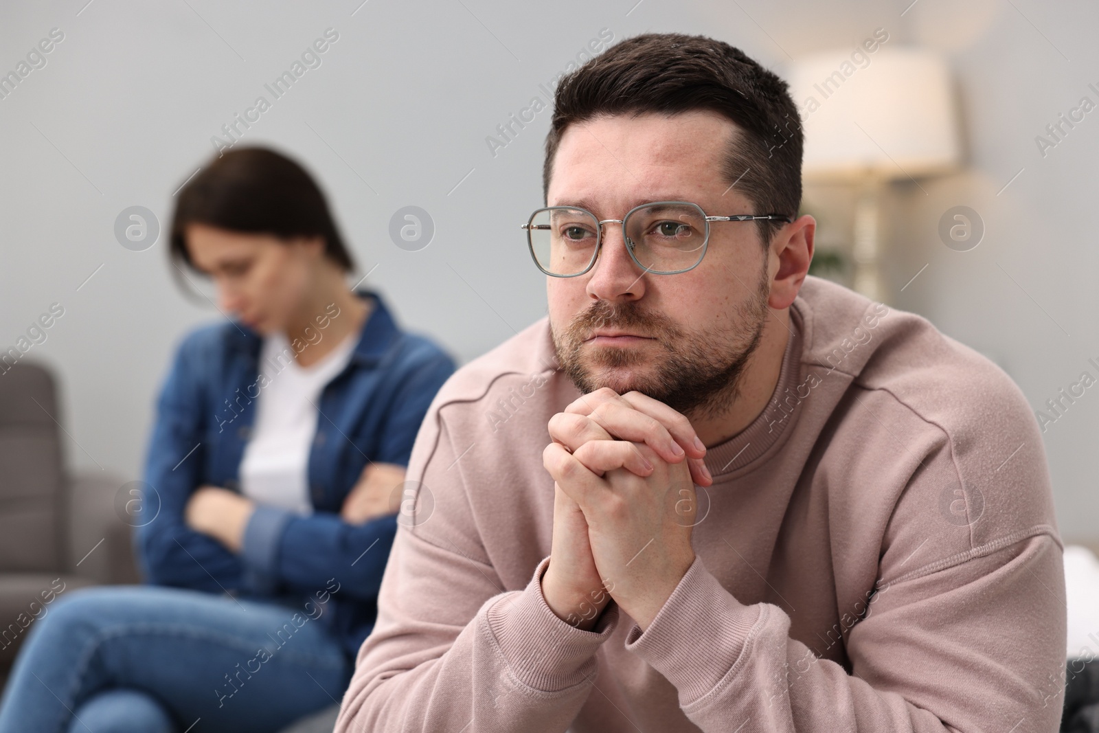 Photo of Offended couple ignoring each other after quarrel in bedroom, selective focus. Relationship problems