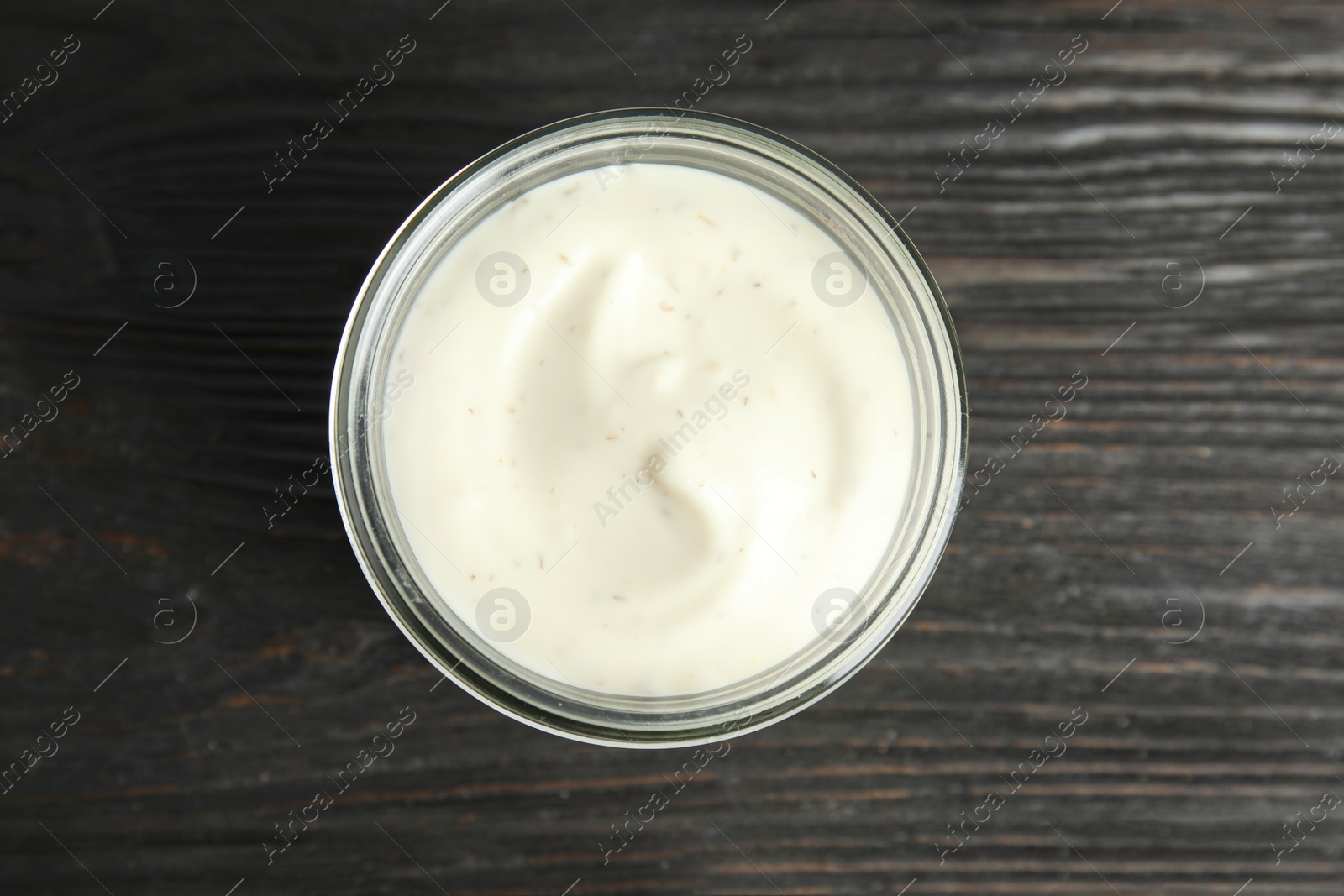 Photo of Jar of garlic sauce on wooden background, top view