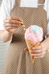 Woman holding waffle cone with cotton candy, closeup