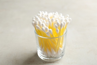 Photo of Glass with cotton swabs on grey background