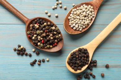 Photo of Aromatic spice. Different peppers in spoons on light blue wooden table, flat lay