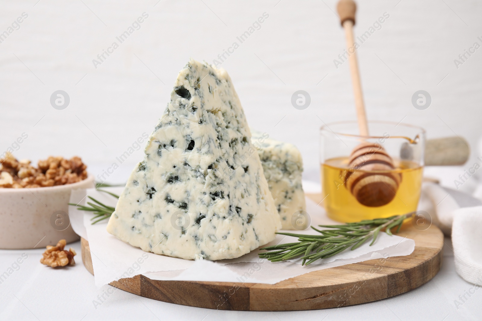 Photo of Tasty blue cheese with rosemary, honey and walnuts on white table