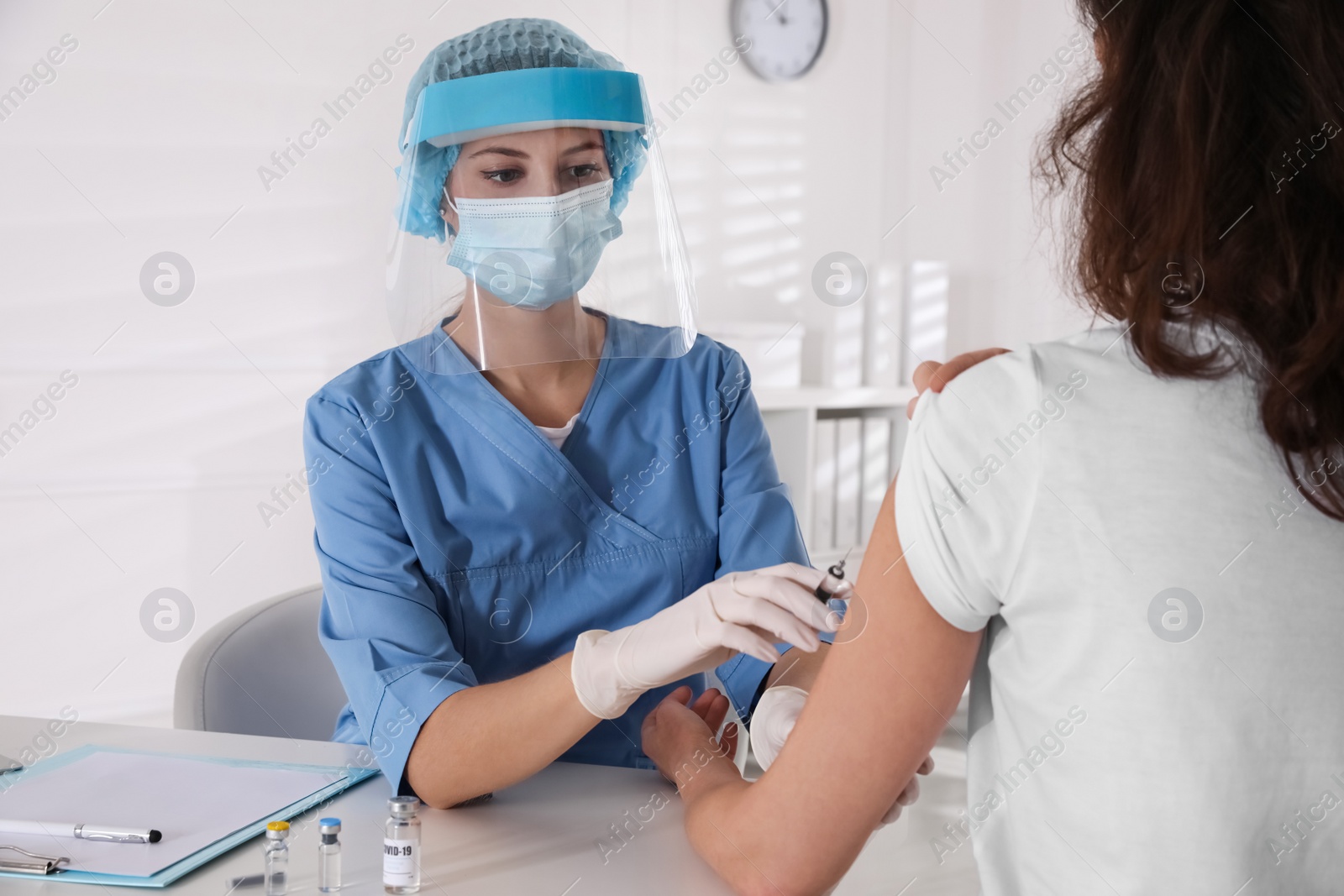 Photo of Doctor vaccinating mature woman against Covid-19 in clinic