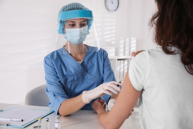 Photo of Doctor vaccinating mature woman against Covid-19 in clinic