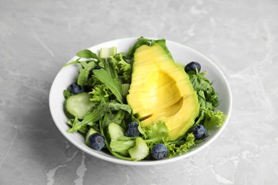 Delicious avocado salad with blueberries in bowl on grey marble table