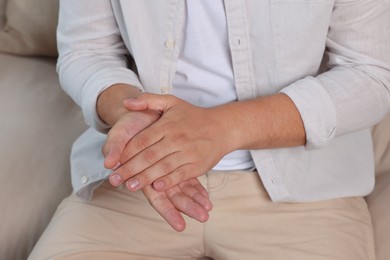 Photo of Man applying hand cream at home, closeup