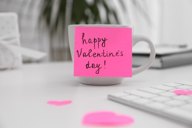 Photo of Memory sticker with phrase Happy Valentine's Day on cup at workplace