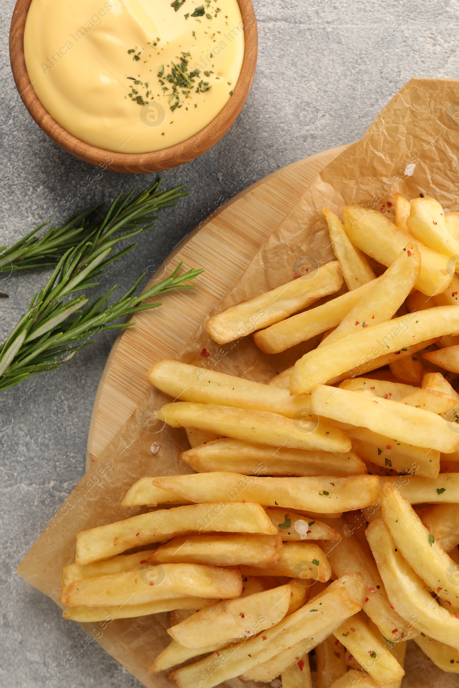Photo of Delicious french fries served with sauce on grey table, flat lay