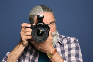 Photo of Male photographer with professional camera on color background