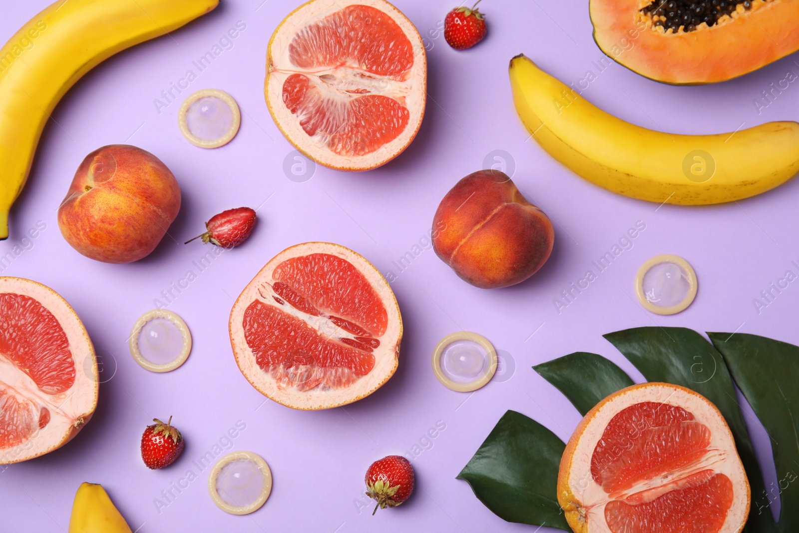 Photo of Flat lay composition with condoms and exotic fruits on lilac background. Erotic concept