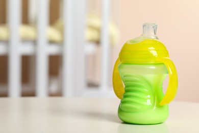Photo of Feeding bottle with milk on white table indoors. Space for text