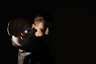 Photo of Professional killer on black background, focus on gun