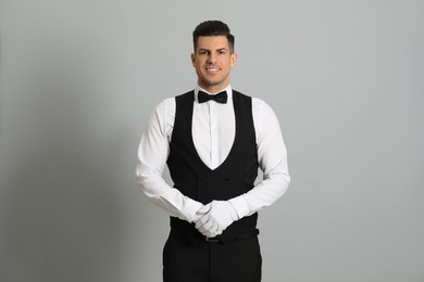 Photo of Handsome butler in elegant uniform on grey background