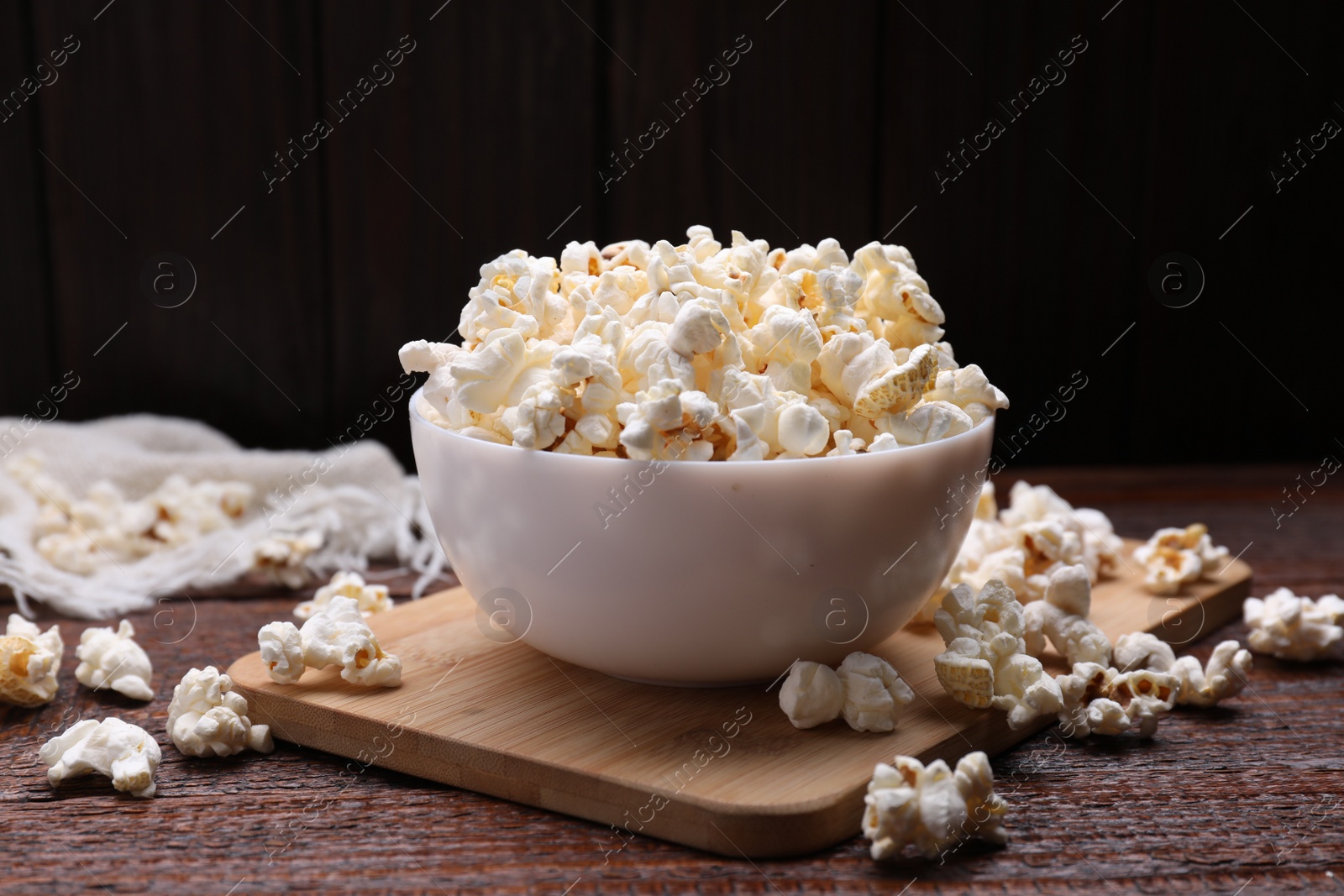 Photo of Bowl of tasty popcorn on wooden table