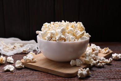Bowl of tasty popcorn on wooden table