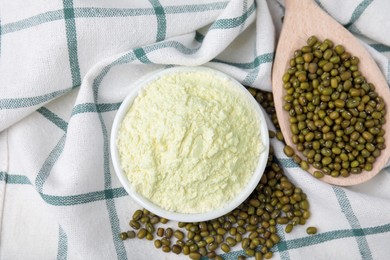 Photo of Bowl of flour and mung beans on cloth, flat lay