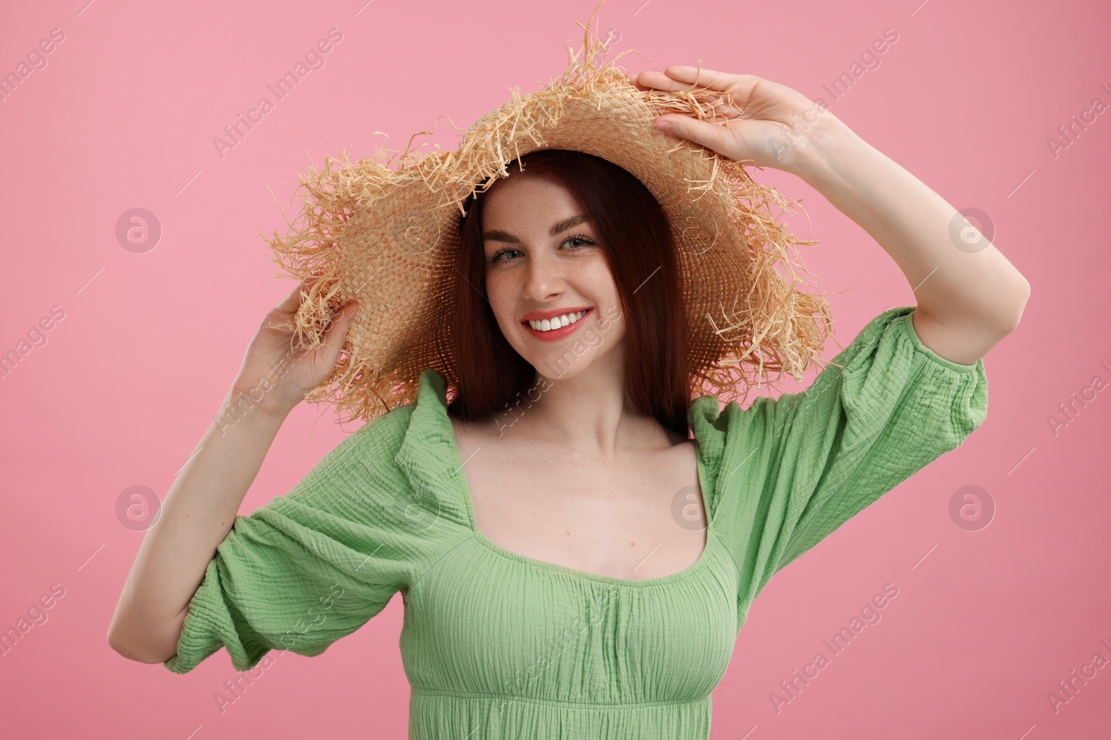 Photo of Portrait of beautiful woman with freckles in straw hat on pink background