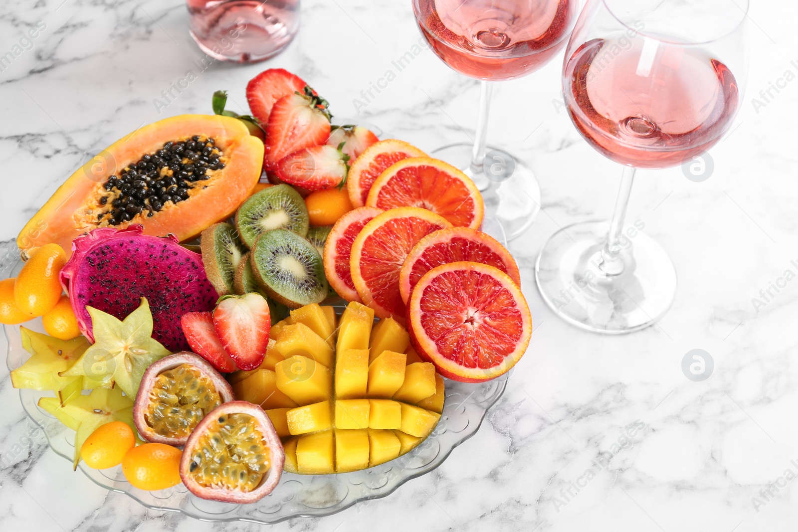 Photo of Delicious exotic fruits and wine on white table