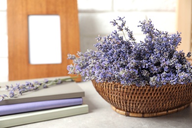 Photo of Composition with basket of fresh lavender flowers on stone table against white brick wall, space for text