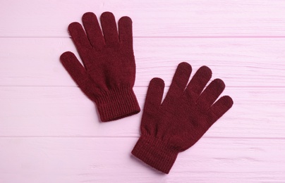 Stylish gloves on pink wooden background, flat lay