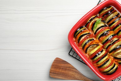 Delicious ratatouille in baking dish on white wooden table, flat lay. Space for text