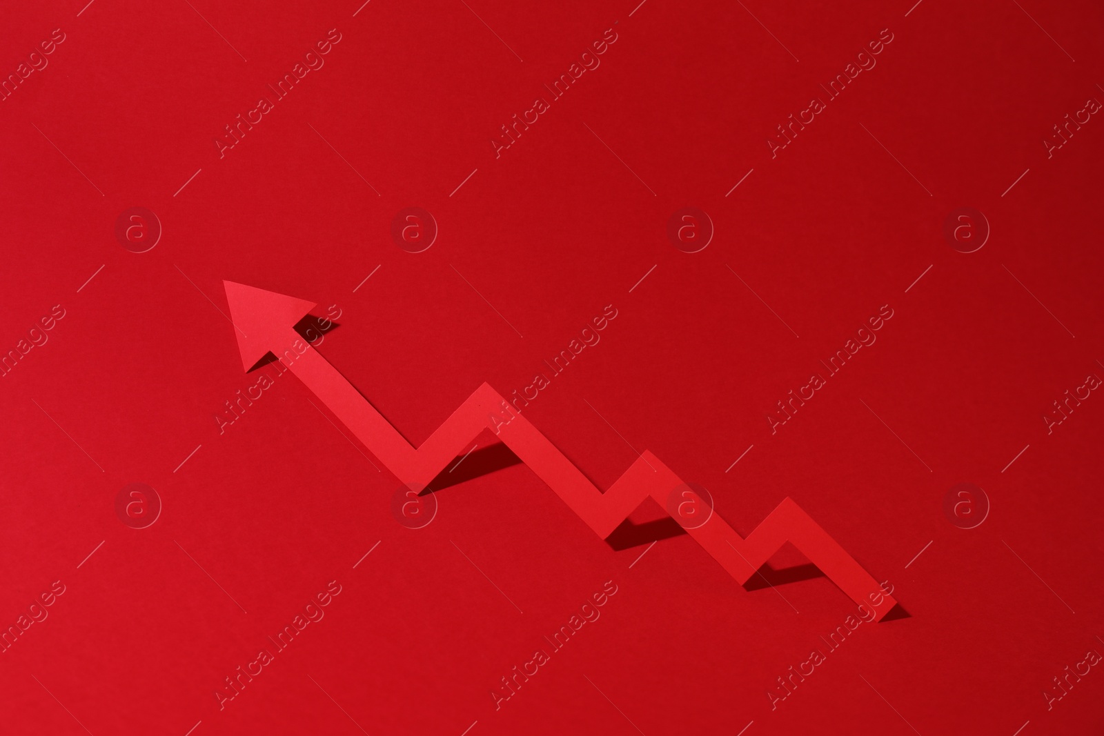 Photo of One zigzag paper arrow on red background