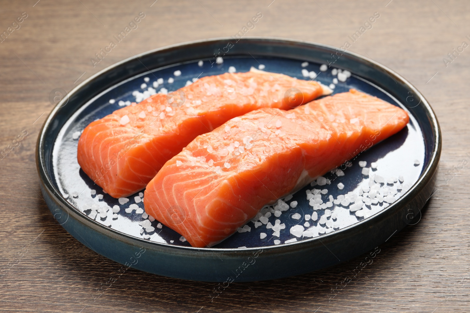 Photo of Fresh raw salmon with salt on wooden table
