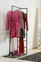 Photo of Clothing rack with colorful sequin party dresses and shoes in boutique