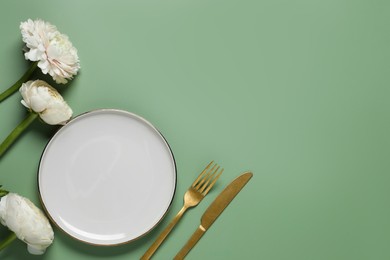 Stylish table setting with cutlery and flowers on olive background, flat lay. Space for text