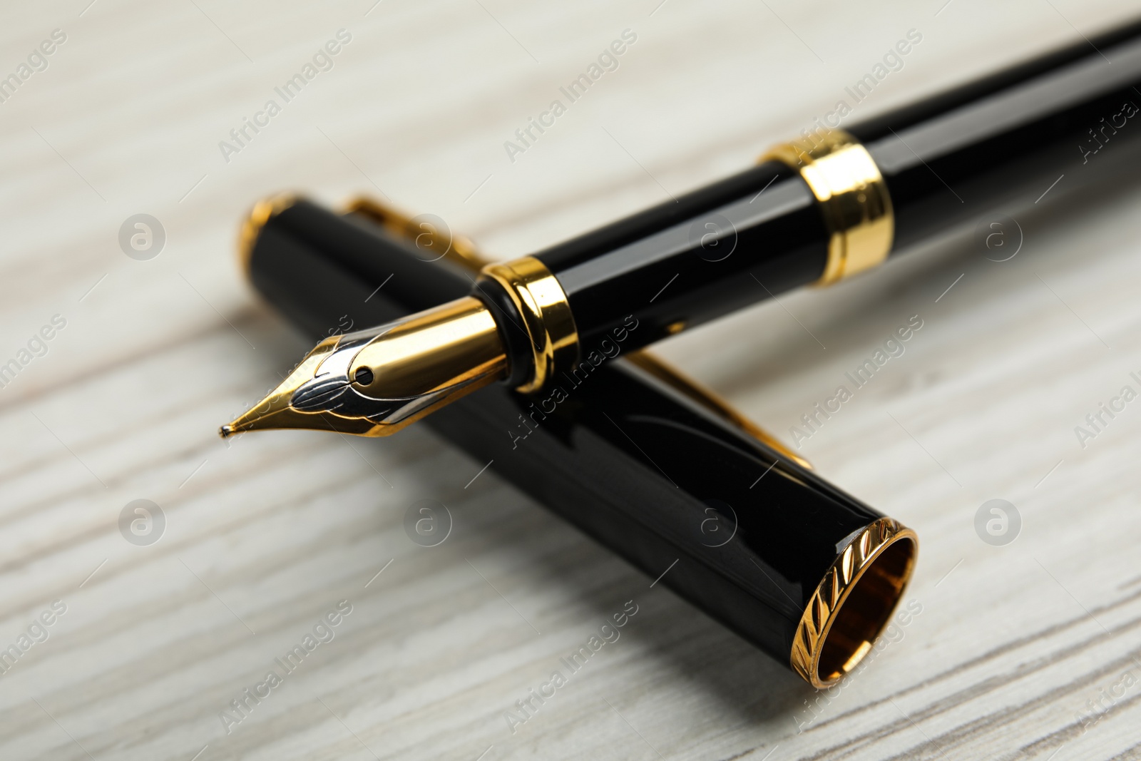 Photo of Beautiful fountain pen with ornate nib on white wooden table, closeup