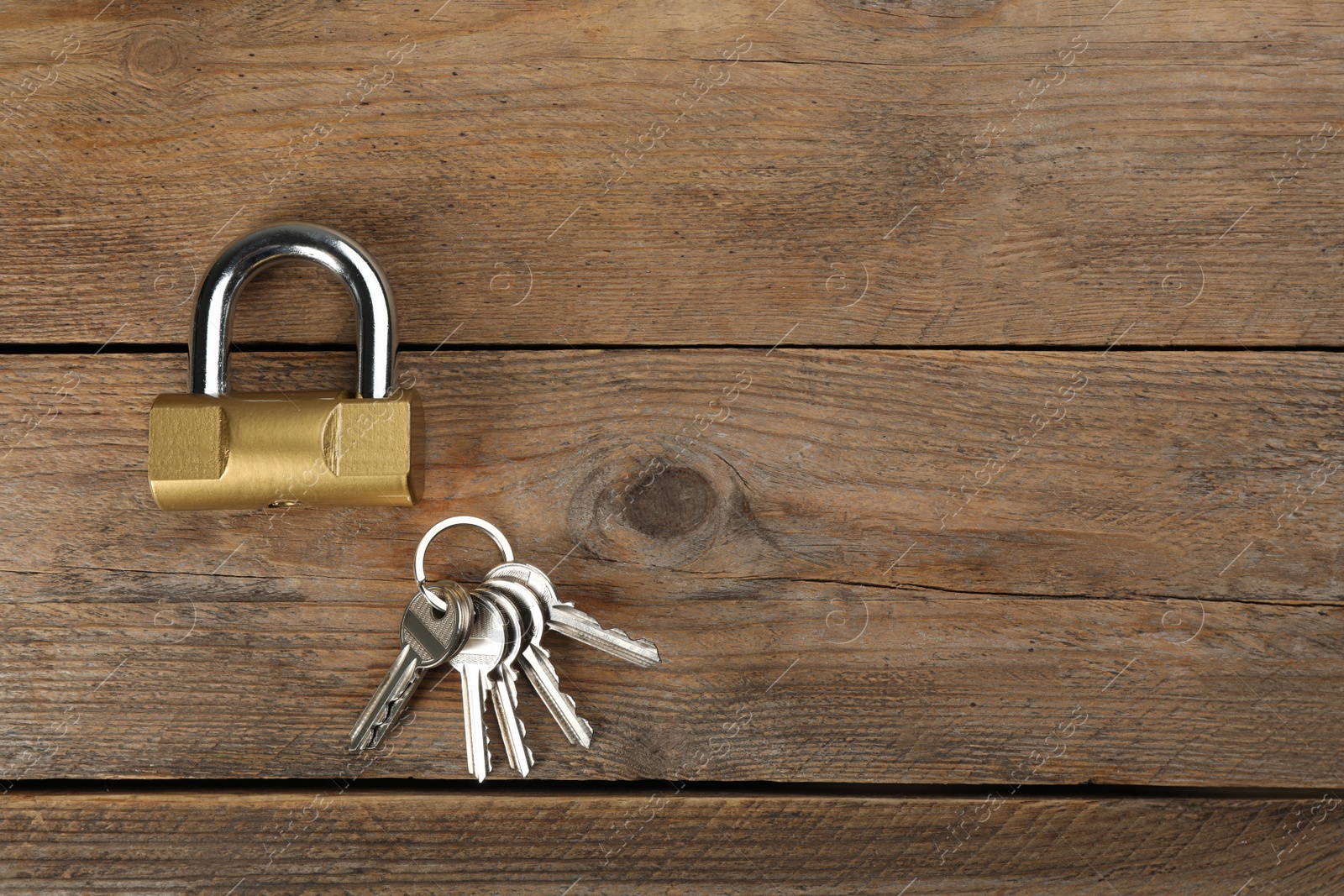 Photo of Modern padlock with keys on wooden table, flat lay. Space for text