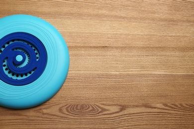 Photo of Blue plastic frisbee disk on wooden background, top view. Space for text