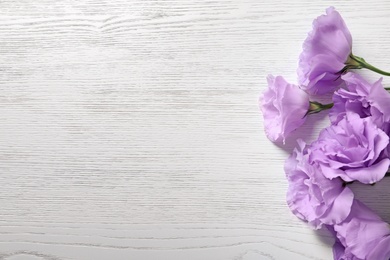 Flat lay composition with beautiful Eustoma flowers on light wooden background