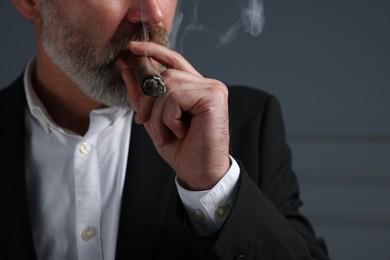 Photo of Bearded man smoking cigar on dark grey background, closeup