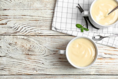 Bowls with vanilla pudding on wooden background