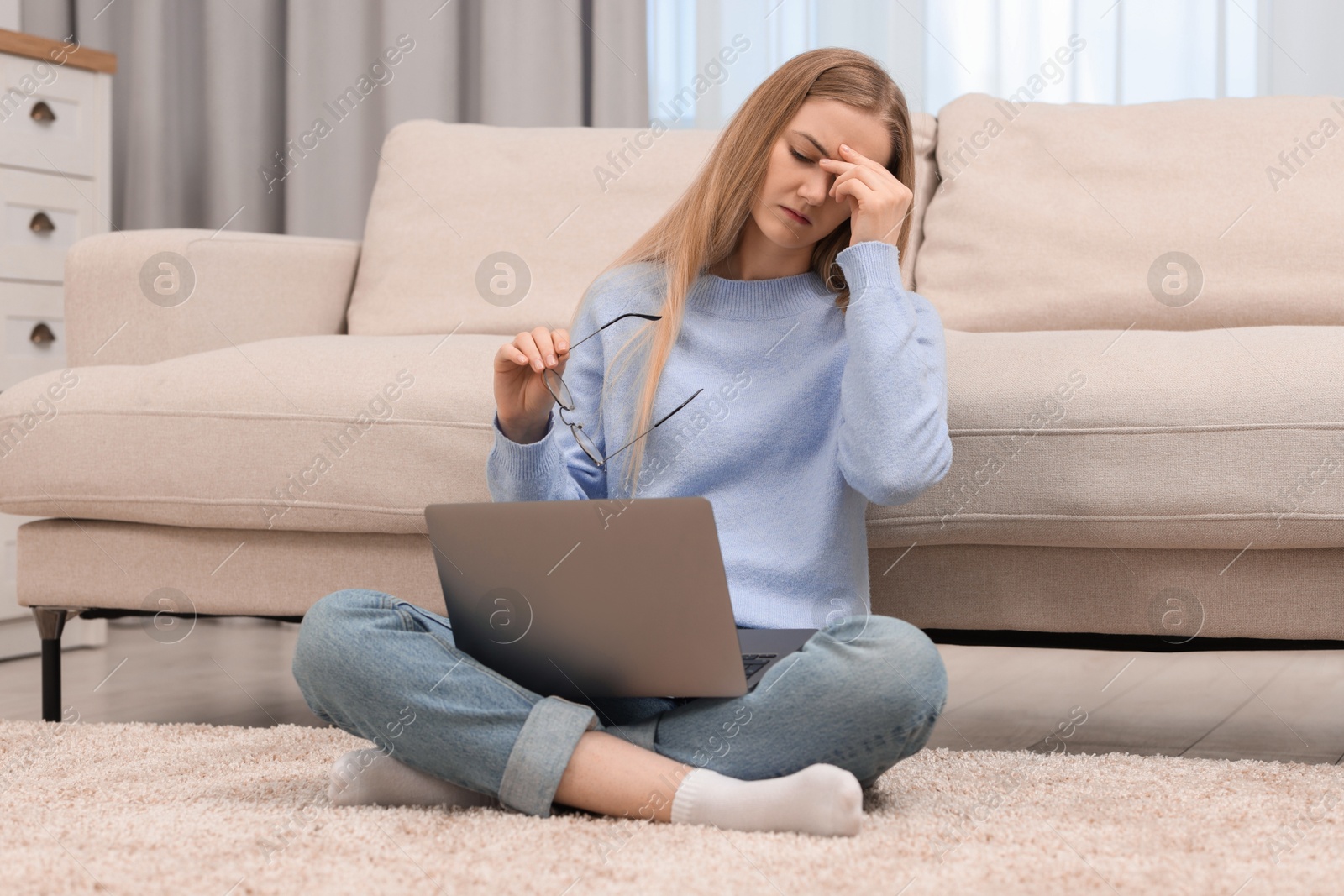 Photo of Overwhelmed young woman sitting with laptop on floor at home