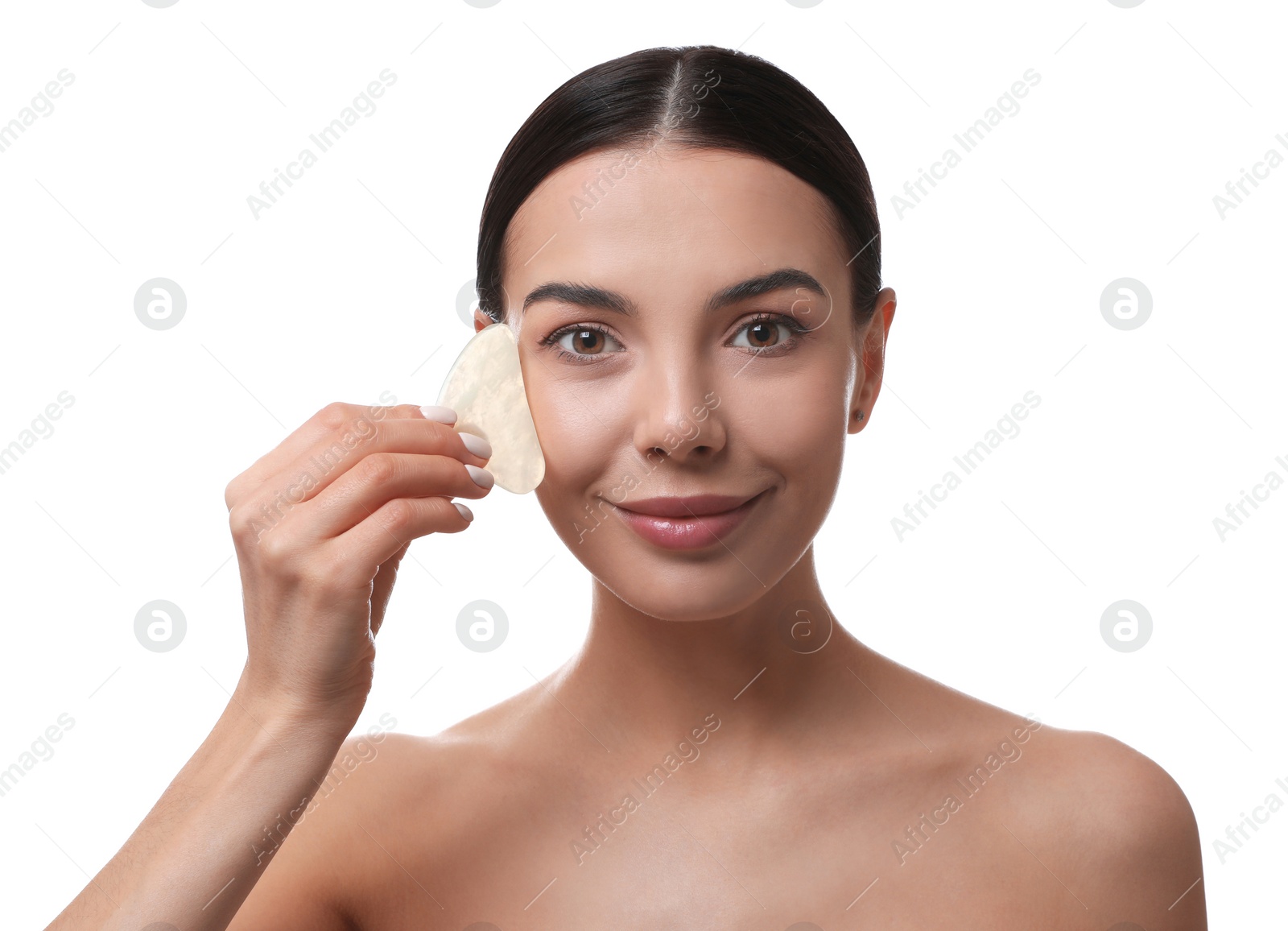 Photo of Beautiful young woman doing facial massage with gua sha tool on white background