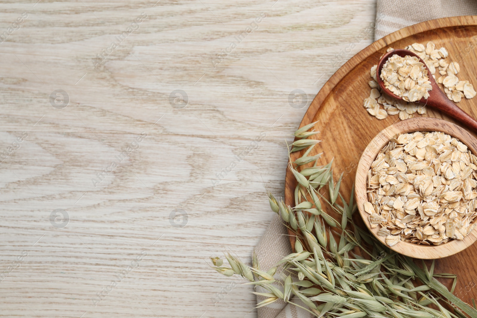 Photo of Oatmeal and branches with florets on wooden table, top view. Space for text