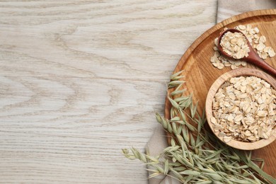 Photo of Oatmeal and branches with florets on wooden table, top view. Space for text